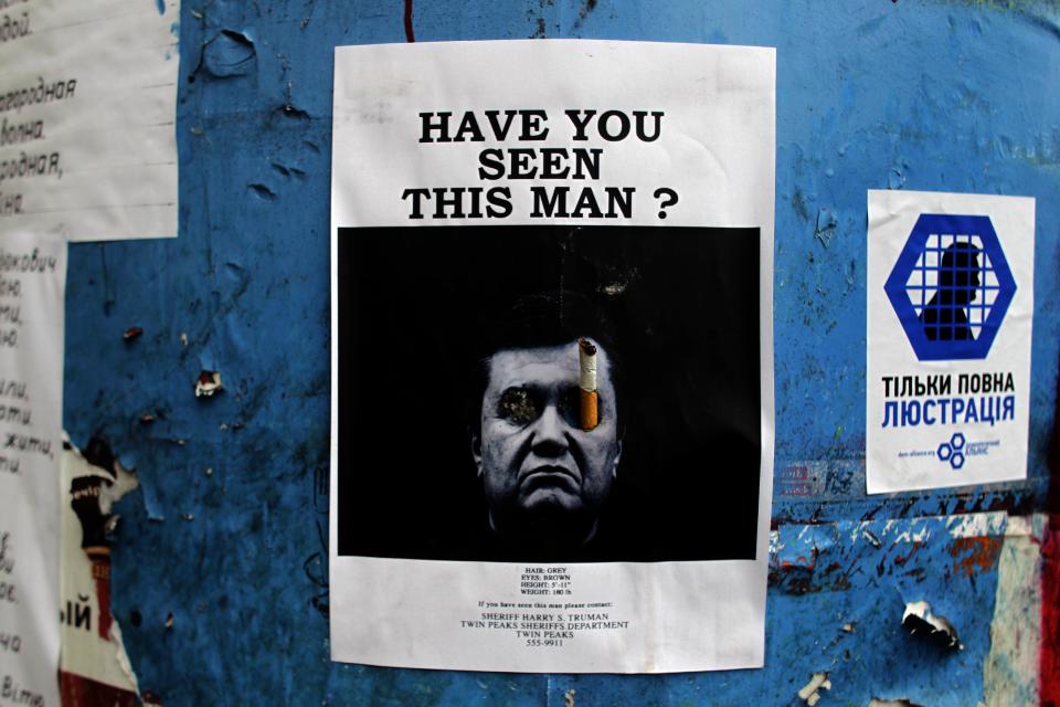 A poster with a photo of fugitive Ukrainian President Viktor Yanukovych, who fled the capital Kiev and went into hiding after months of protests against his government, is seen fixed onto a barricade in central Kiev, Ukraine, Thursday, Feb. 27, 2014. Ukraine put its police on high alert after dozens of armed pro-Russia men stormed and seized local government buildings in Ukraine's Crimea region early Thursday and raised a Russian flag over a barricade. (AP Photo/Marko Drobnjakovic)