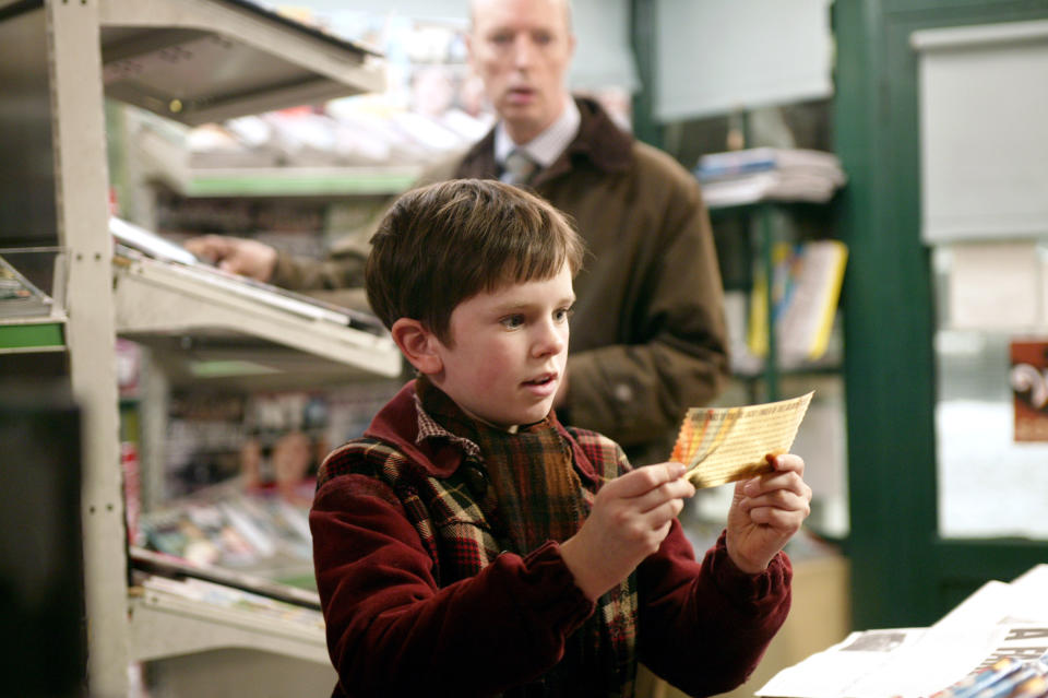 close up of Freddie holding the golden ticket with short brown hair