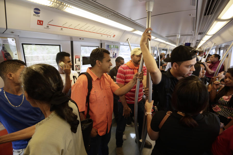 In this April 25, 2019 photo, independent presidential candidate Ricardo Lombana, center in orange shirt, travels on the subway to a campaign rally in Panama City. Lombana, a 45-year-old lawyer, has rejected large campaign contributions and has not advertised on TV. (AP Photo/Arnulfo Franco)