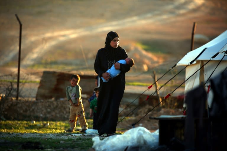 A Syrian woman carries her child at a temporary refugee camp in the village of Ain Issa, housing people who fled Islamic State group's Syrian stronghold Raqa