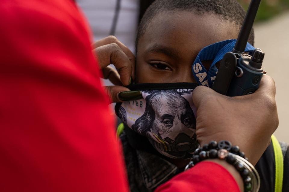 Principal Stephanie Gaines adjusts a student's face mask at Thirkell Elementary-Middle School in Detroit on Friday, Nov. 13, 2020.