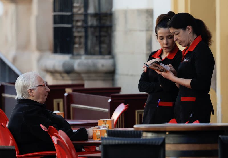 A pensioner sits, as he looks at waitresses in the terrace of a bar in Ronda