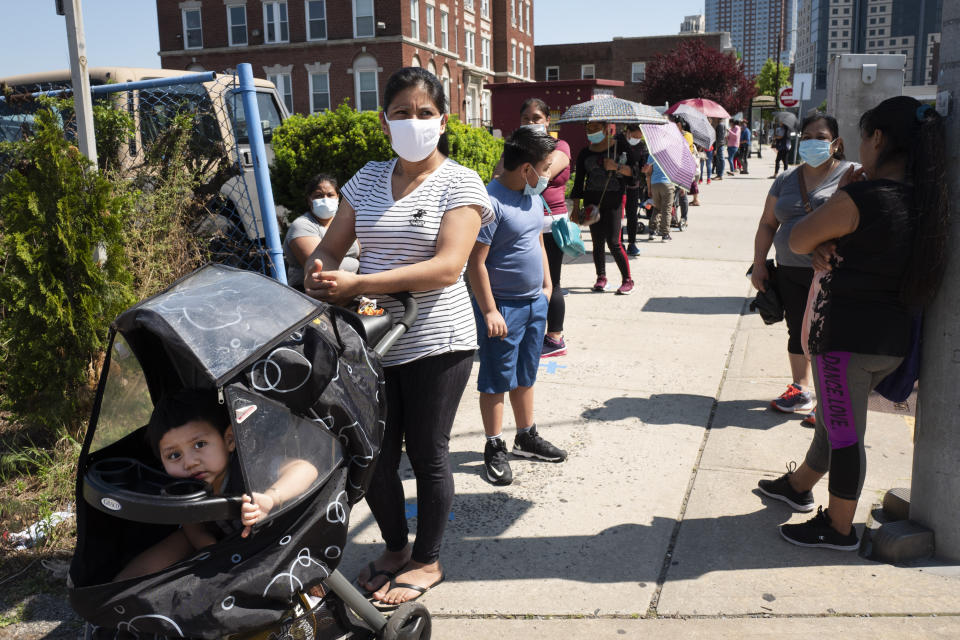 People wait in line to pick up bags of food and diapers at the Fuller Center for Housing in New Rochelle, N.Y., Tuesday, June 9, 2020, during the coronavirus pandemic. (AP Photo/Mark Lennihan)