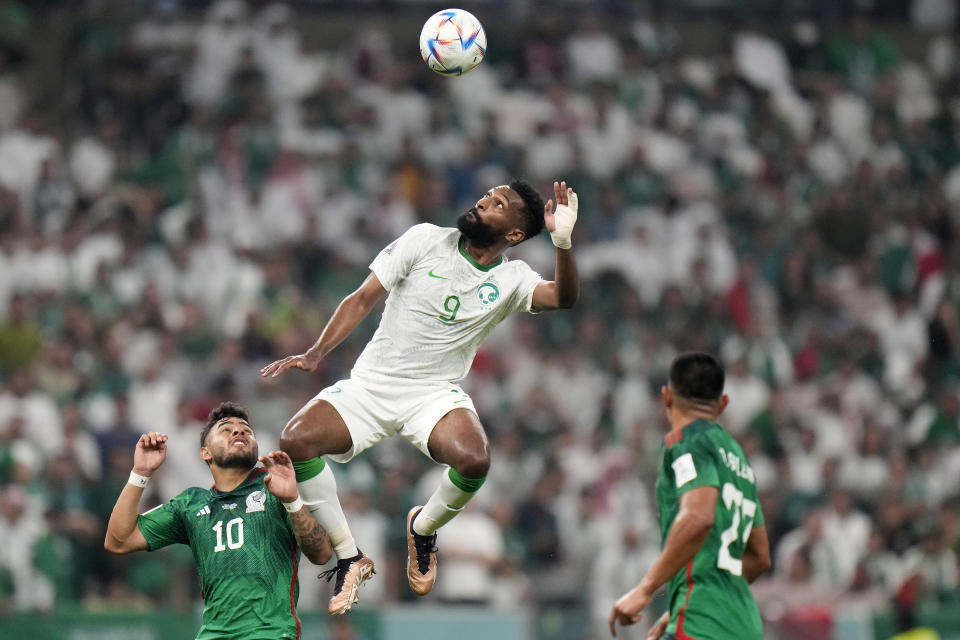Mexico's Alexis Vega, left, and Mexico's Jesus Gallardo, right, watch Saudi Arabia's Firas Al-Buraikan jumping for the ball during the World Cup group C soccer match between Saudi Arabia and Mexico, at the Lusail Stadium in Lusail, Qatar, Wednesday, Nov. 30, 2022. (AP Photo/Moises Castillo)
