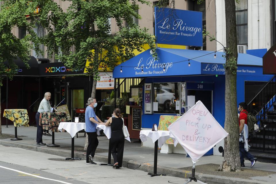 Clientes con mascarillas están parados en mesas afuera de restaurantes el jueves 28 de mayo de 2020 en Nueva York. (AP Foto/Frank Franklin II)