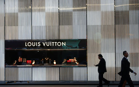 FILE PHOTO: Men walk past a boutique of the Louis Vuitton luxury goods company in Beijing, China, November 30, 2016. REUTERS/Thomas Peter/File Photo