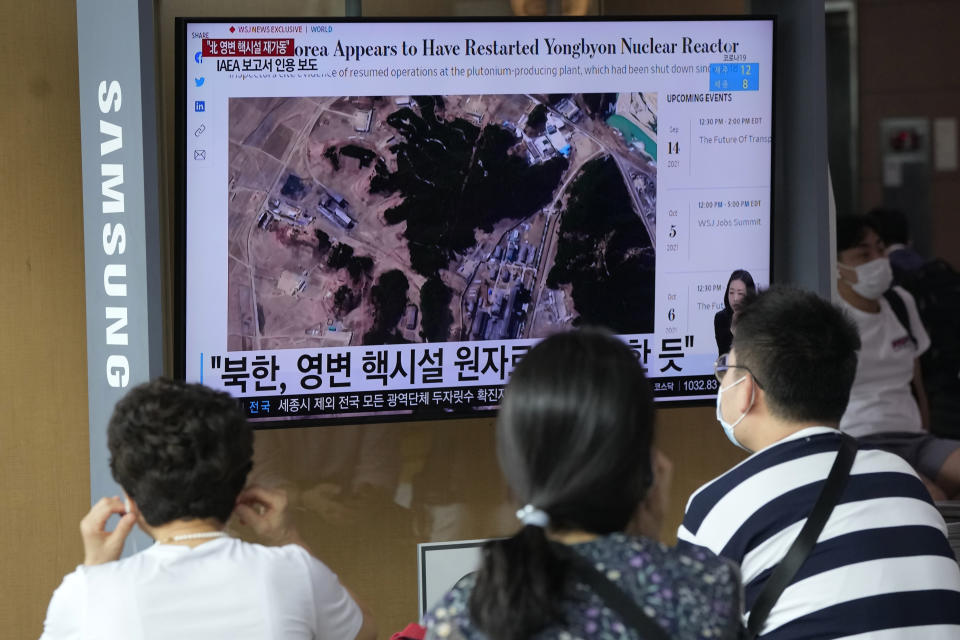 People watch a TV screen showing a file satellite image of the Yongbyon nuclear site in North Korea during a news program at the Seoul Railway Station in Seoul, South Korea, Monday, Aug. 30, 2021. North Korea appears to have restarted the operation of its main nuclear reactor used to produce weapons fuels, the U.N. atomic agency said, as the North openly threatens to enlarge its nuclear arsenal amid long-dormant nuclear diplomacy with the United States. Korean letters read: "North Korea's Yongbyon nuclear facility seems to have restarted." (AP Photo/Ahn Young-joon)
