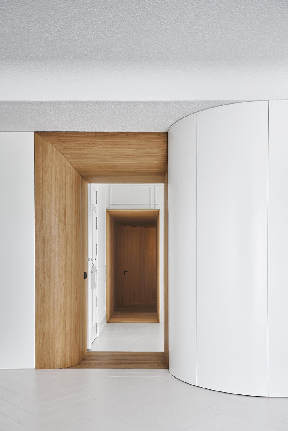 curved white wall next to a wood doorway