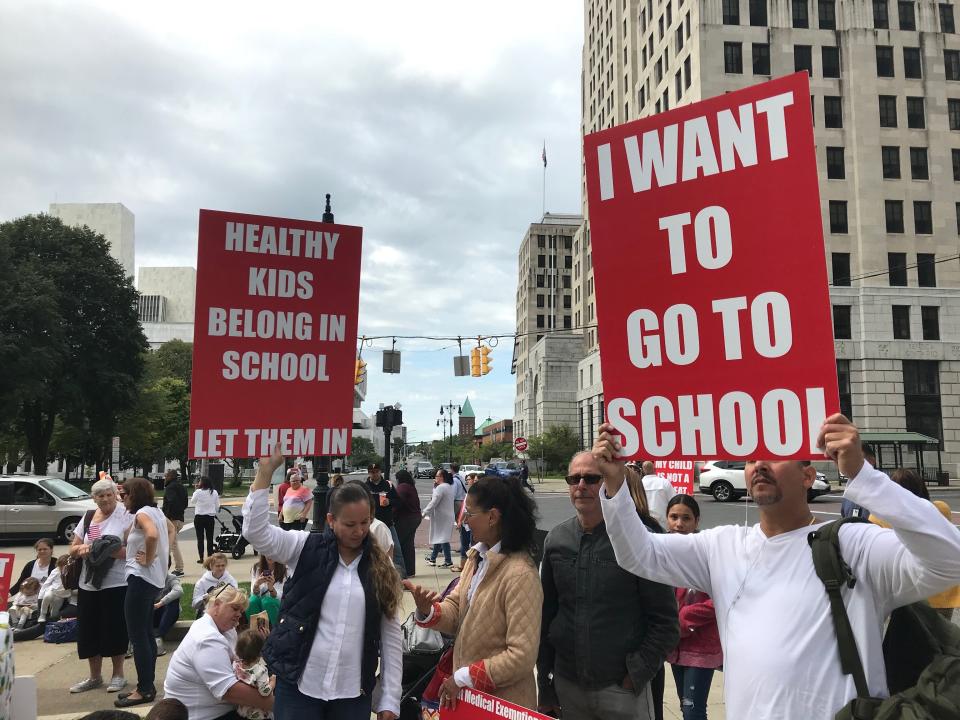 Protestors in 2019 hold signs in opposition to a New York state law approved that year that banned religious exemptions from school vaccinations during a rally outside the state Education Building in Albany