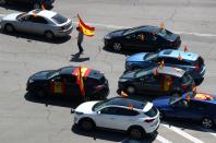 Un manifestante con mascarilla camina portando una bandera de España entre coches en Madrid