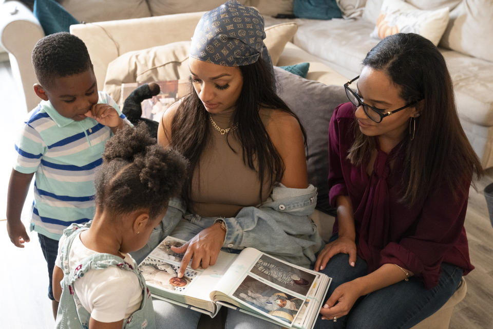Katherine Guzmán (centro) y su hermana Jennifer miran un álbum familiar de fotos junto a los medio hermanos que adoptaron tras la muerte de su madre, Zavion (izq) y Jazzmyn, el 17 de septiembre del 2020 en Newark, Nueva Jersey. (AP Photo/Mary Altaffer)