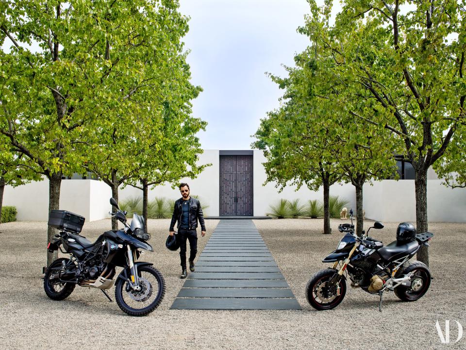 Theroux at the main entrance with his BMW (left) and Ducati (right) motorcycles. For the bronze front doors, Shadley took inspiration from the backdrop of Johnny Carson’s Tonight Show set from the 1960s.