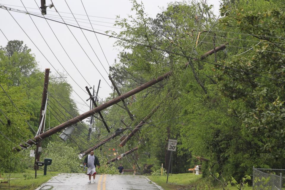 A man makes his way down Jackson Street among downed power lines in Tupelo, Miss., following a tornado, Monday, April 28, 2014. A dangerous storm system that spawned a chain of deadly tornadoes killed dozens from the Midwest to the Deep South. (AP Photo/The Northeast Mississippi Daily Journal, Thomas Wells)