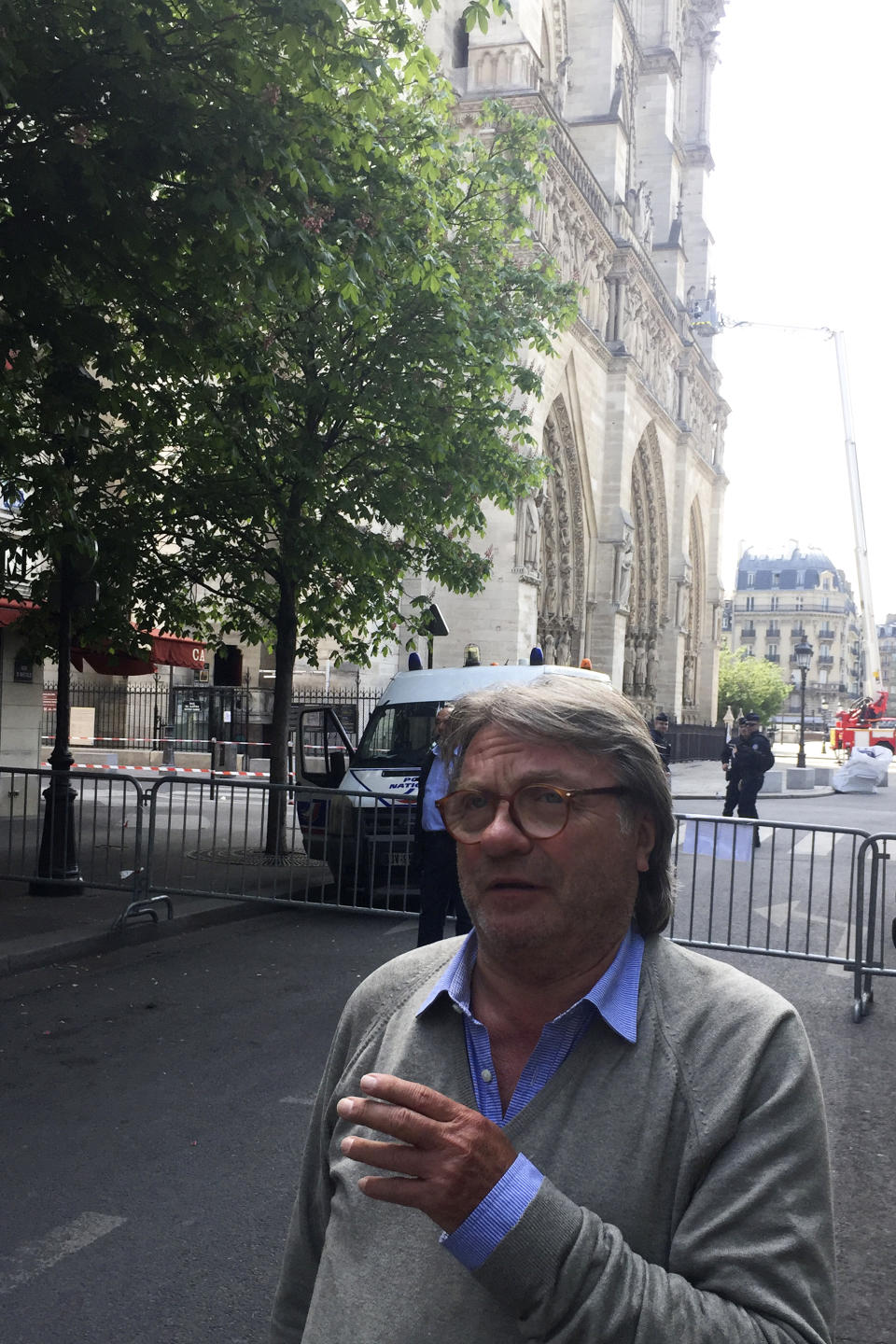 Patrice Le Jeune of Notre Dame neighborhood merchants' association walks in a street neat the cathedral, behind, in Paris, Thursday, April 18, 2019. Since Monday's fire, half the island in the middle of the Seine has been closed to visitors. Residents who had never met before suddenly find themselves the only customers of restaurants and cafés normally filled with tourists. At Quasimodo Notre Dame bar, named for Victor Hugo's hunchback, storekeepers commiserate. (AP Photo/Nicolas Vaux-Montagny)