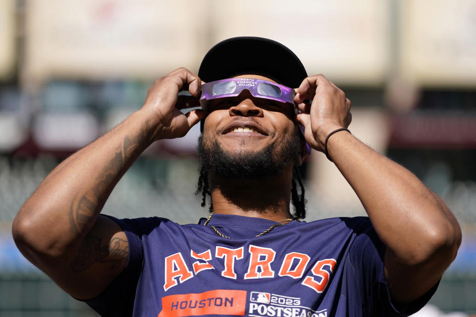 Houston Astros outfielder Corey Julks uses protective glasses to look at the solar eclipse during baseball practice in Houston, Saturday, Oct. 14, 2023. The Astros are scheduled to play the Texas Rangers in Game 1 of MLB's American League Championship Series on Sunday. (AP Photo/Tony Gutierrez)