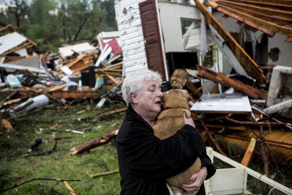 Constance Lambert embraces her dog after finding it alive when returning to her destroyed home in Tupelo, Miss., Monday, April 28, 2014. Lambert was at an event away from her home when the tornado struck and rushed back to check on her pets. (AP Photo/The Commercial Appeal, Brad Vest)