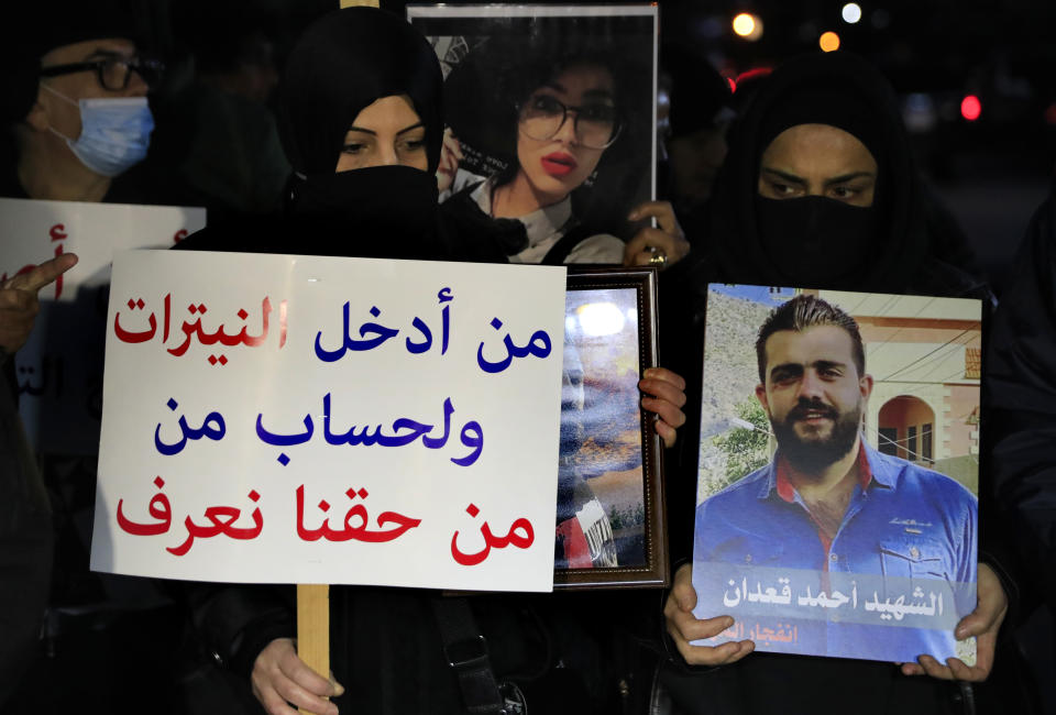 Relatives of victims of the Aug. 4, 2020 Beirut port explosion hold portraits of their loved one who killed during the explosion, during a sit-in outside the Justice Palace, in Beirut, Lebanon, Thursday, Feb. 18, 2021. Lebanon's highest court asked the chief prosecutor investigating last year's massive Beirut port explosion to step down, following legal challenges by senior officials he had accused of negligence that led to the blast, a judicial official and the country's official news agency said. The Arabic placard on poster reads:"Who brought the nitrates and for who? We have a right to know." (AP Photo/Hussein Malla)