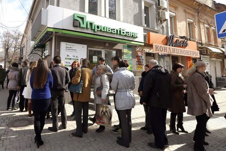 People stand in line to withdraw money at an automated teller machine (ATM) of Ukrainian bank Privatbank in Simferopol, in this March 14, 2014 file photo. REUTERS/Vasily Fedosenko/Files