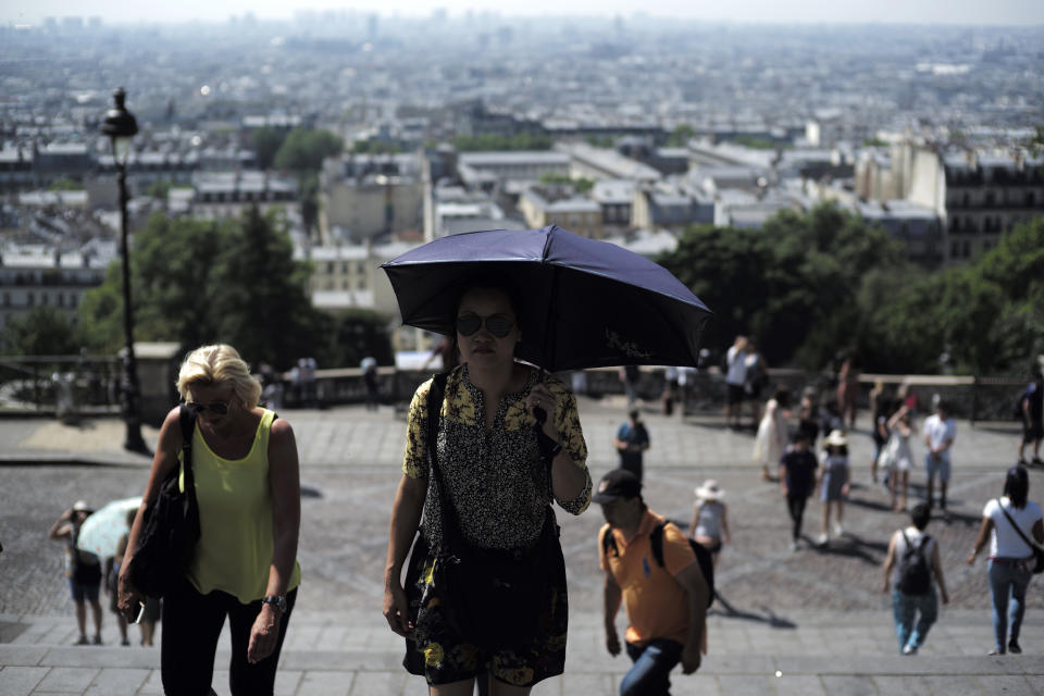 Tourists climb the steps leading to the Sacre Coeur basilica Wednesday, June 26, 2019 in the Montmartre district of Paris. More than half of France is on alert for high temperatures and the hot weather is expected to last until the end of the week. (AP Photo/Kamil Zihnioglu)