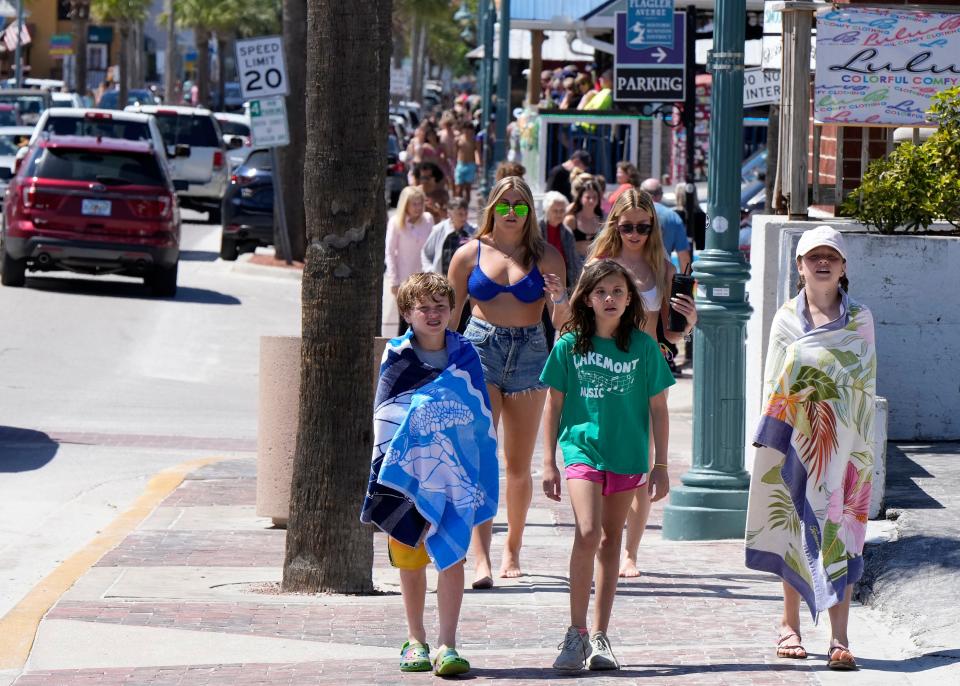 Spring break students share the sidewalk with families along Flagler Avenue in New Smyrna Beach.