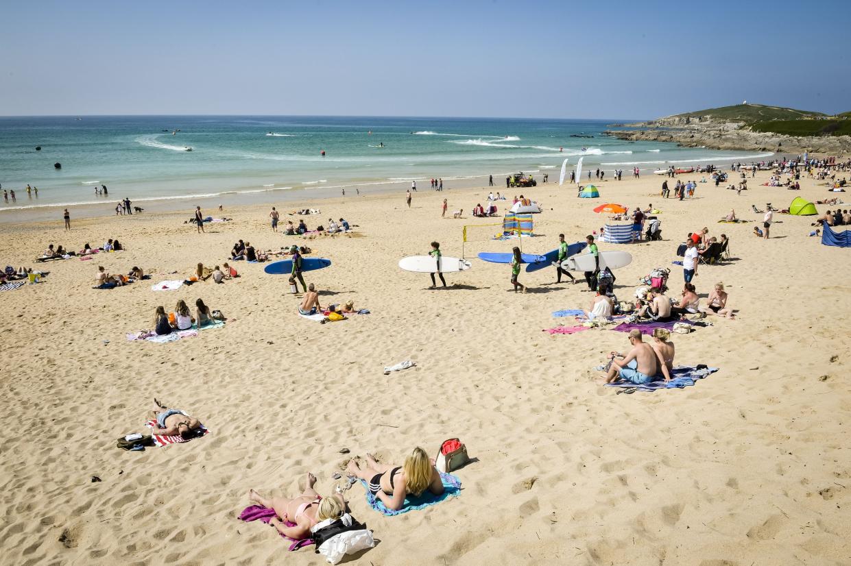 People relax in the sun at Fistral Beach, Cornwall.