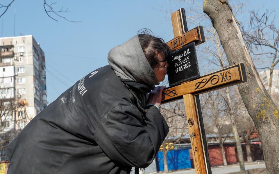 A woman at the grave of her mother, who was killed by Russian shelling in Mariupol - Alexander Ermochenko/Reuters