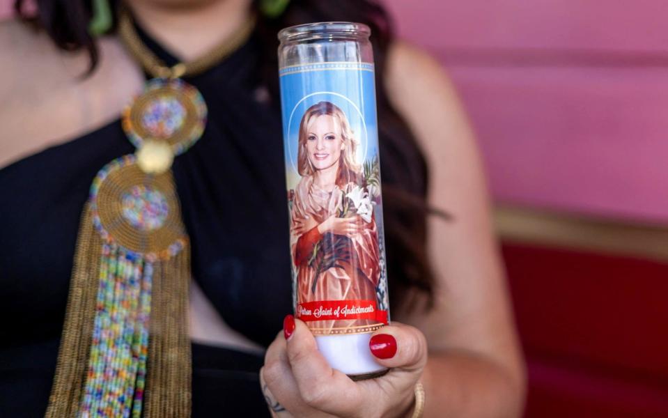 A woman holds a candle depicting Stormy Daniels as the "Patron Saint of Indictments" outside of AllWays Lounge and Cabaret