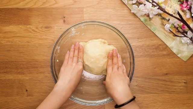 Kneading dough with hands in a glass bowl