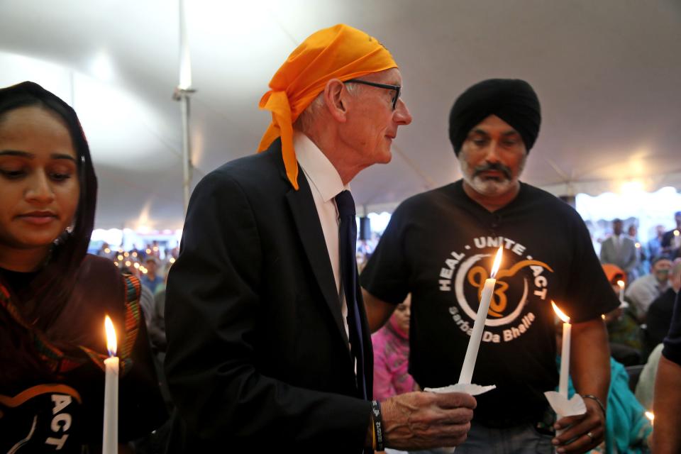 Wisconsin Gov. Tony Evers, center, and Pardeep Singh Kaleka, right, attend the Oak Creek Sikh Memorial Anniversary Candlelight Remembrance Vigil at the Sikh Temple of Wisconsin on Friday, Aug. 5, 2022, on the 10-year anniversary of a mass shooting at the temple.
