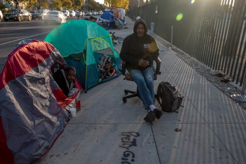Los Angeles, CA - February 16: Freddie McConnell Jr., 43, left, Jawonna Smith, 33, and Joe Maddox, 61, living under tent on sidewalk behind Academy Museum of Motion Pictures, wait for buses to ferry them to motel under Mayor Karen Bass's initiative "Inside Safe" on Thursday, Feb. 16, 2023 in Los Angeles, CA. (Irfan Khan / Los Angeles Times)