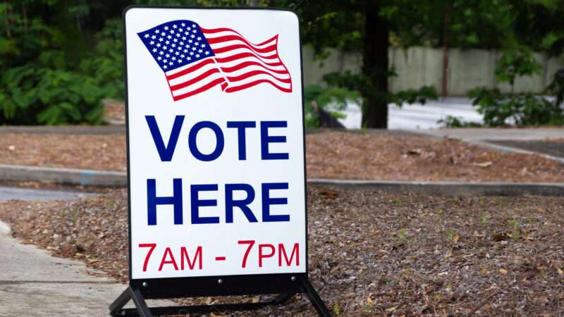 A sign for a polling place that reads VOTE HERE 7AM-7PM