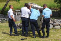 French gendarmes and police inspect a large piece of plane debris which was found on the beach in Saint-Andre, on the French Indian Ocean island of La Reunion, July 29, 2015. REUTERS/Zinfos974/Prisca Bigot