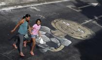 A woman walks with her daughter over graffiti referencing the 2014 World Cup in Rio de Janeiro May 22, 2014. Rio de Janeiro is one of the host cities for the 2014 World Cup in Brazil. REUTERS/Ricardo Moraes (BRAZIL - Tags: SPORT SOCCER WORLD CUP SOCIETY)