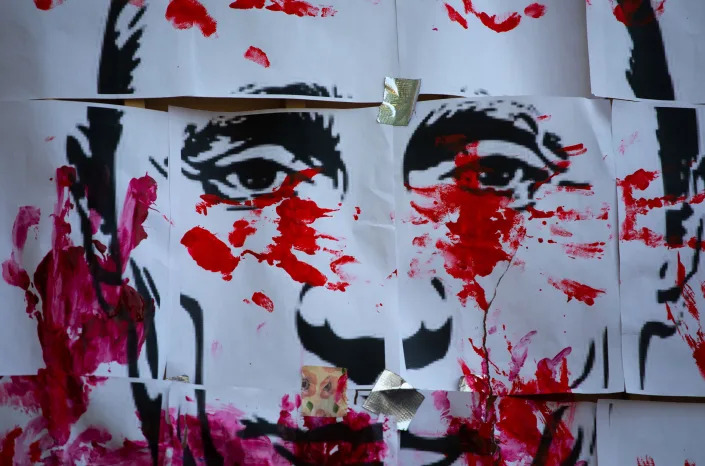 A banner printed with the image of Russian President, Vladimir Putin, is painted with fake blood.