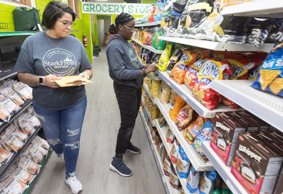 Shania Mays, left, cashier, and Ruth Dele-Oni , Urban Farm Coordinator for Stark Fresh, work to price groceries on the shelves minutes before the Alliance store was set to open.