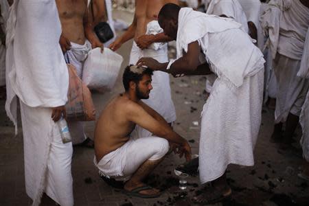 A Muslim pilgrim has his head shaved after casting pebbles at a pillar that symbolizes Satan during the annual haj pilgrimage, on the first day of Eid al-Adha in Mina, near the holy city of Mecca October 15, 2013. REUTERS/Ibraheem Abu Mustafa