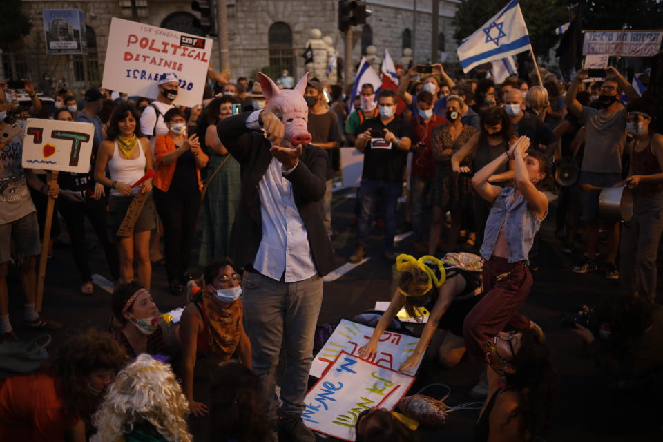 Demonstrators, defying orders to maintain social distancing requirements, chant slogans and blow horns outside Prime Minister's residence in Jerusalem, Tuesday, July 14, 2020. Thousands of Israelis demonstrated outside of the official residence of Benjamin Netanyahu, calling on the embattled Israeli leader to resign as he faces a trial on corruption charges and grapples with a deepening coronavirus crisis. (AP Photo/Ariel Schalit)