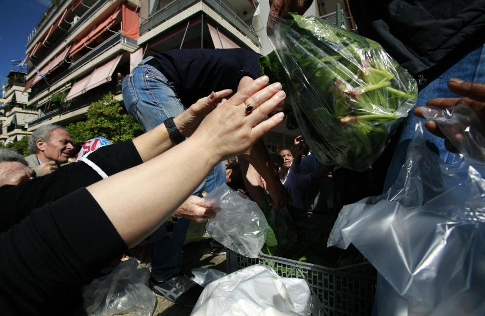 Greek farmers' market vendors distribute free produce as part of a protest in Athens, Wednesday, April 30, 2014, after their trading association launched an indefinite strike Monday. The market vendors are the latest professional group in Greece to protest a sweeping liberalization drive demanded by rescue creditors. (AP Photo/Dimitri Messinis)