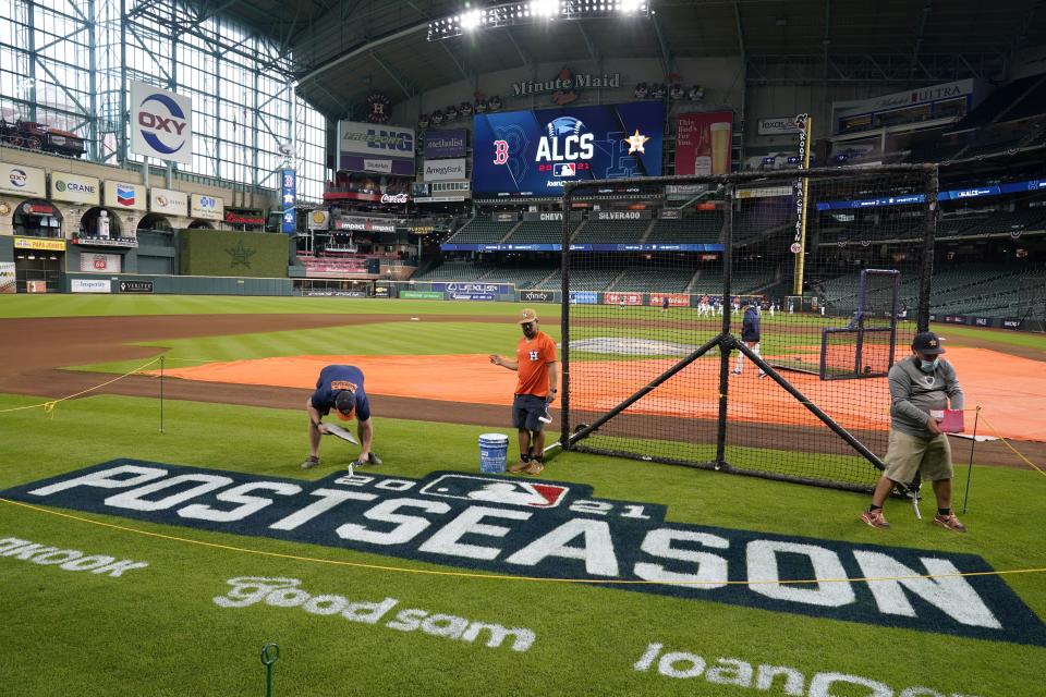 Grounds crew personnel apply the final touches to a postseason field logo at Minute Maid Park before baseball practice in Houston, Thursday, Oct. 14, 2021. The Houston Astros host the Boston Red Sox in Game 1 of the American League Championship Series on Friday. (AP Photo/Tony Gutierrez)