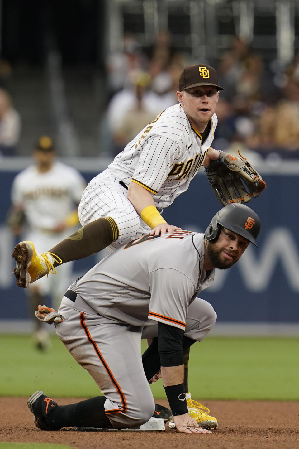 San Diego Padres second baseman Jake Cronenworth, top, watches his throw to first for a double play as San Francisco Giants' Brandon Belt looks on after sliding in late to second base during the fourth inning of a baseball game Saturday, May 1, 2021, in San Diego. Giants' Wilmer Flores was out at first on the play. (AP Photo/Gregory Bull)