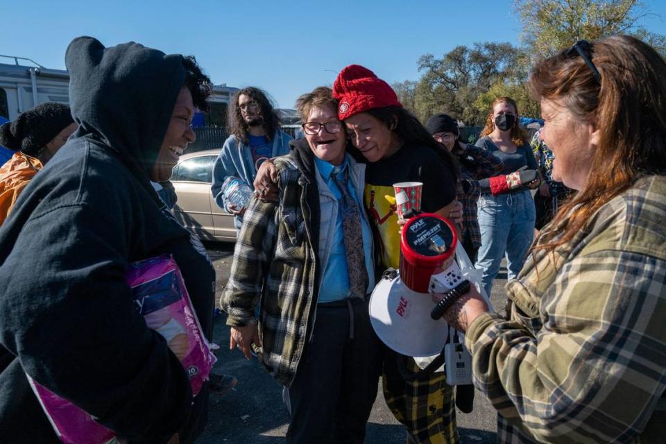 Camp Resolution residents Joyce Williams and Desiree Pryor embrace in November 2022 after Tammy Myler, right, thanked everyone who spoke at a Sacramento City Council meeting where a motion was approved to postpone removing the homeless encampment.