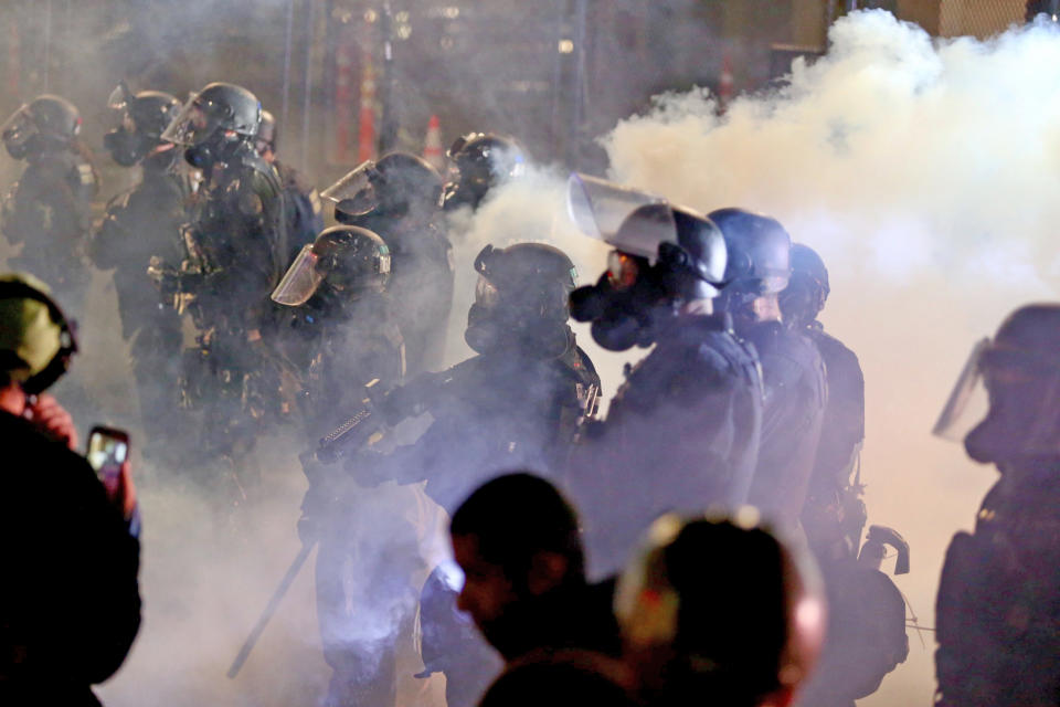 Portland police and protesters clash during a demonstration, early Thursday Aug. 13, 2020, in downtown, Portland. Officers used tear gas to break up the crowd of several hundred people who gathered near the Mark O. Hatfield U.S. Courthouse, the neighboring Multnomah County Justice Center and a nearby police precinct station. (Sean Meagher/The Oregonian via AP)