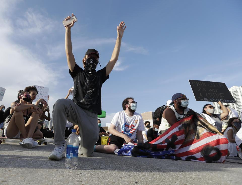 Protesters kneel on an off ramp of I-95 highway after blocking traffic during a demonstration, Saturday, May 30, 2020, downtown in Miami. Protests were held throughout the country over the death of George Floyd, a black man who died after being restrained by Minneapolis police officers on May 25.(AP Photo/Wilfredo Lee)