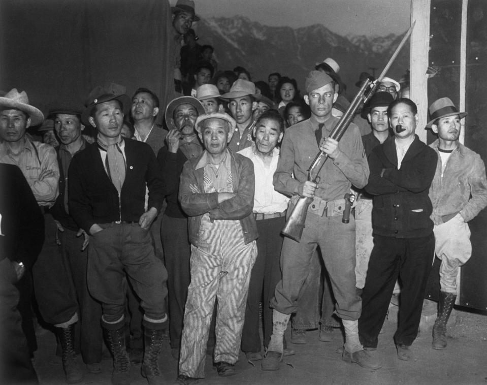 <p>An American soldier guarding a crowd of Japanese-Americans at an internment camp at Manzanar, Calif., during World War II. (Photo: Hulton-Deutsch/Hulton-Deutsch Collection/Corbis via Getty Images) </p>