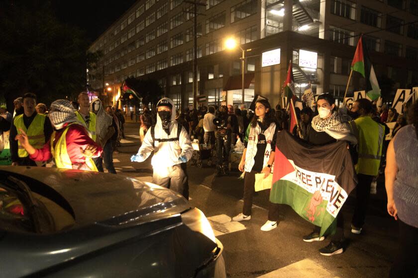 LOS ANGELES, CA - DECEMBER 15, 2023 - Members of CeaseFireLA stop a car from driving while marching to demand that Israel and the United States enact a permanent and lasting ceasefire in Gaza near LAX in Los Angeles on December 15, 2023. They eventually helped the car make a U-Turn and avoid the protesters. (Genaro Molina / Los Angeles Times)