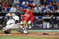 Cincinnati Reds' Jake Fraley (27) scores against Miami Marlins catcher Jacob Stallings (58) during the seventh inning of a baseball game, Friday, May 12, 2023, in Miami. (AP Photo/Michael Laughlin)