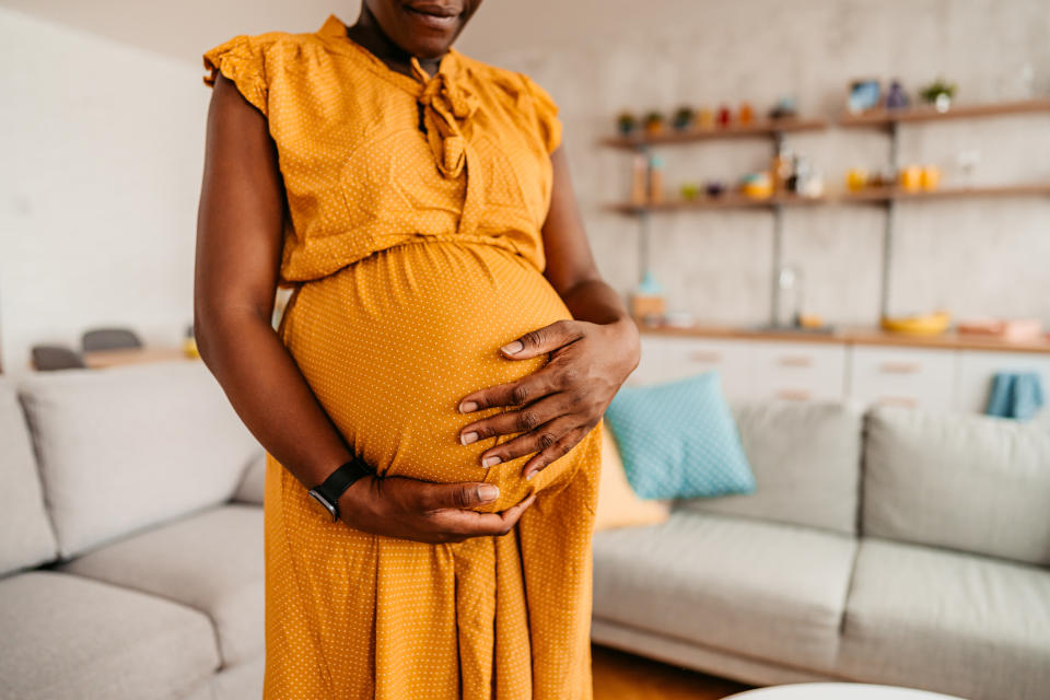 person with their arms on their pregnant belly