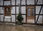 A Christmas tree leans against a damaged house in the village of Schuld in the Ahrtal valley, southern Germany, Tuesday, Dec.14, 2021. Amid the mud and debris still clogging the streets from last summer's devastating floods, residents of the Ahr Valley in western Germany are trying to spark some festive cheer with Christmas trees. (Photo/Michael Probst)