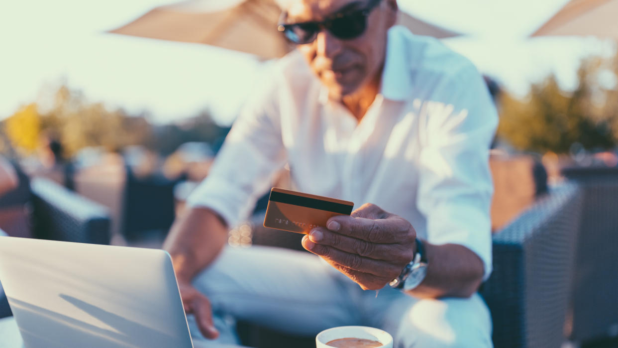 Man at cafe using credit card and laptop for online payments.