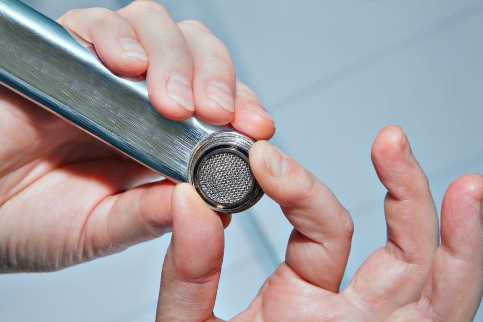 Person removing an aerator from a faucet.